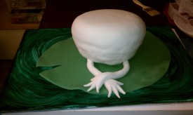 Next, she is covered with fondant. Her arms are shaped from fondant as well and crossed delicately in front.